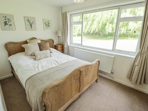 a bedroom with a bed with a large window at Lake View Cottage in Alford