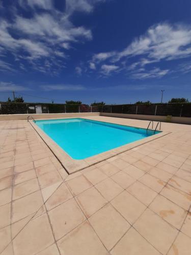 une grande piscine sur un patio carrelé dans l'établissement SANTOLINES : Charmante maisonnette avec piscine proche Etang, à Marseillan