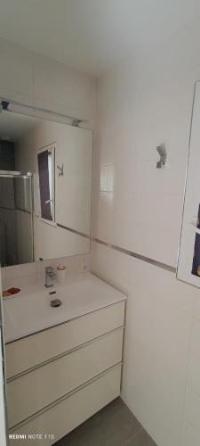 une salle de bain blanche avec un lavabo et un miroir dans l'établissement Maison de Sophie, à Maraussan