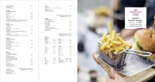 a page of a menu with a hand holding a basket of fries at Crowne Plaza Rugao in Nantong