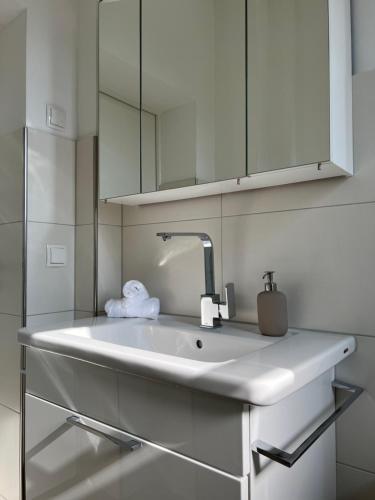 ein weißes Waschbecken in einem Badezimmer mit einem Spiegel in der Unterkunft Ruhrperle Apartment 1 Essen in Essen