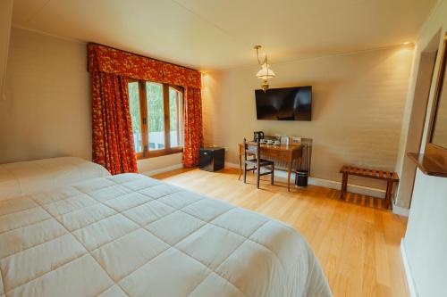 a bedroom with a bed and a desk and a window at Kau Yatún Hotel Boutique in El Calafate