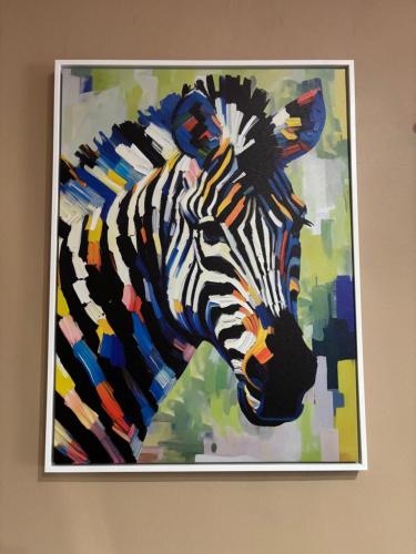 a painting of a zebra is hanging on a wall at Cityscape Apartment in Trofwi