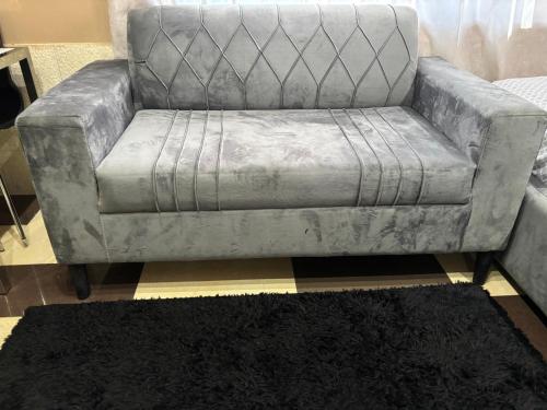 a silver couch sitting in a living room with a rug at Cityscape Apartment in Trofwi