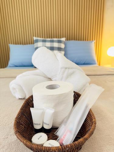 a basket of toilet paper and two cups on a bed at Dahican Beach Homestay in Mati