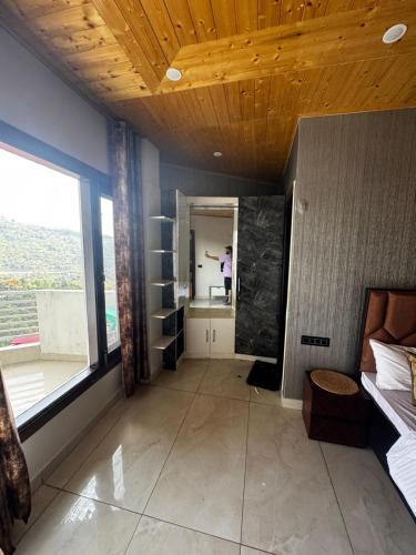 a room with a large window and a person standing in the mirror at The Ivyview Villa Kumarhatti Barog Near Kasauli in Barog