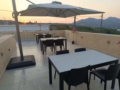 a patio with tables and chairs and an umbrella at Evans Villas in Gramvousá