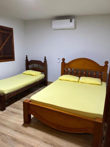two beds in a room with yellow sheets at Chácara Recanto Ribeiro in Pirenópolis