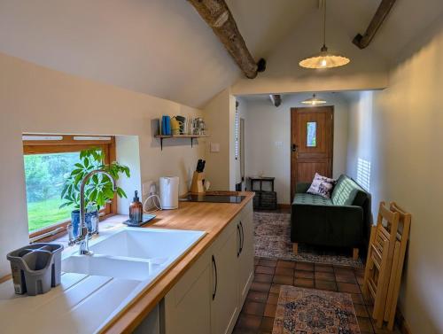 a kitchen with a sink and a living room at The Piggery, located at the foot of the Malvern's in Mathon