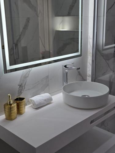 une salle de bain blanche avec un lavabo et un miroir dans l'établissement Oasis Dubai Piscine Arena P Expo, à Pérols