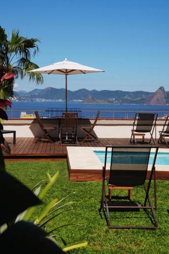 a patio with chairs and an umbrella and a pool at Gerthrudes Bed & Breakfast in Rio de Janeiro