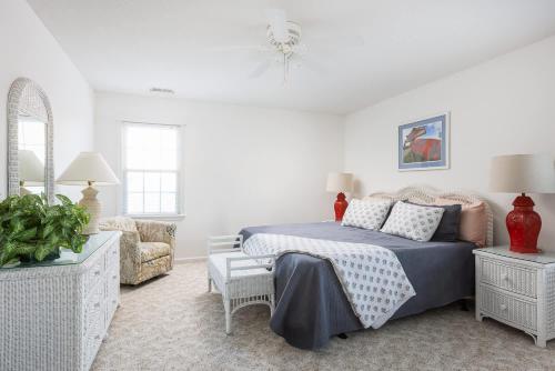 a white bedroom with a bed and a chair at 5 Min Walk to Nags Head Beach and Centrally Located in Nags Head