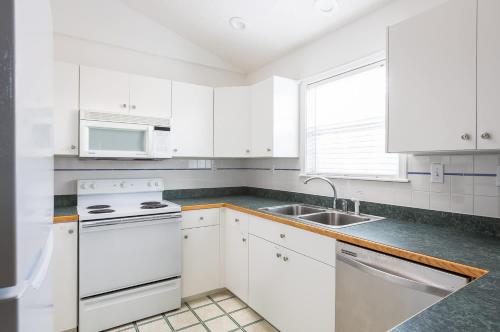 a white kitchen with white appliances and a sink at 5 Min Walk to Nags Head Beach and Centrally Located in Nags Head