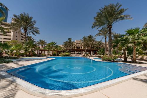 a swimming pool in a resort with palm trees at The Diplomat Radisson Blu Hotel Residence & Spa in Manama