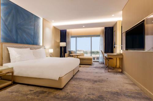a hotel room with a large bed and a desk at The Diplomat Radisson Blu Hotel Residence & Spa in Manama