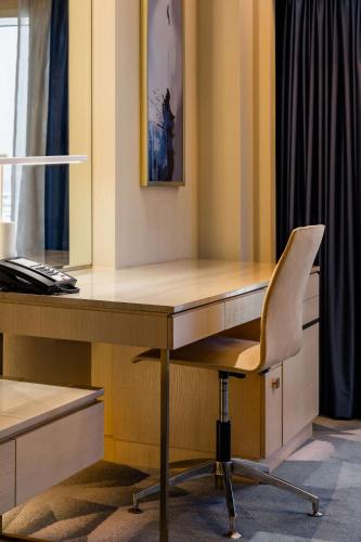 a desk with a chair next to a desk with a computer at The Diplomat Radisson Blu Hotel Residence & Spa in Manama