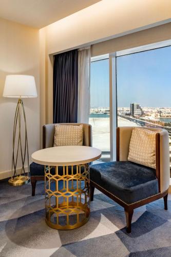 a hotel room with a table and chairs and a large window at The Diplomat Radisson Blu Hotel Residence & Spa in Manama