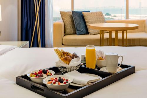 a tray of food on a bed with fruit and bread at The Diplomat Radisson Blu Hotel Residence & Spa in Manama