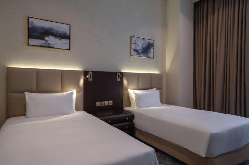 a hotel room with two beds in a room at The Diplomat Radisson Blu Hotel Residence & Spa in Manama