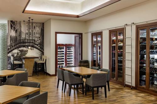 a dining room with tables and chairs and a wine cellar at The Diplomat Radisson Blu Hotel Residence & Spa in Manama