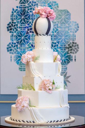 a three tiered white wedding cake with pink flowers at The Diplomat Radisson Blu Hotel Residence & Spa in Manama