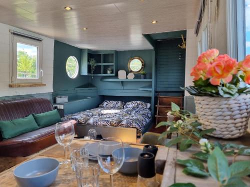a living room with a bed and a table with wine glasses at Houseboat Meuse in Vireux-Wallerand