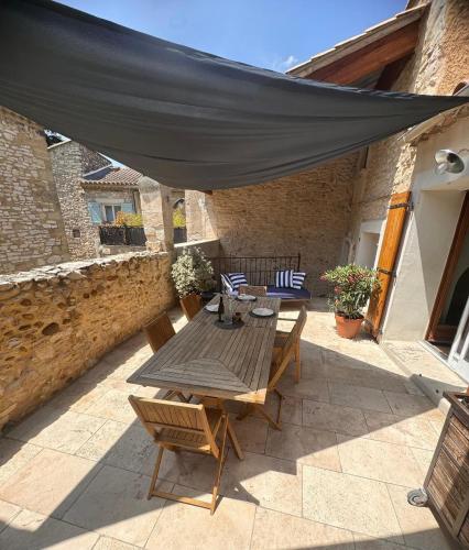 d'une terrasse avec une table et des chaises sous un auvent. dans l'établissement Maison traditionnelle Gardoise avec Jacuzzi 5 personnes 3 chambres, à Saint-Laurent-des-Arbres