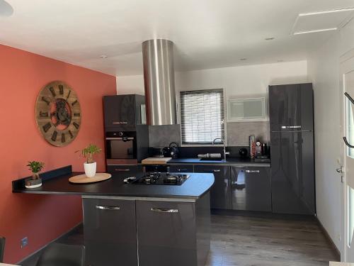 une grande cuisine avec des appareils noirs et des murs rouges dans l'établissement Villa de caractères,piscine, vue sur le luberon,3 chambres, à Cheval-Blanc