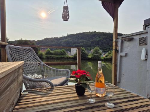 a bottle of wine and two glasses on a wooden table at Houseboat Meuse in Vireux-Wallerand