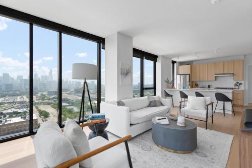a living room with white furniture and large windows at Foundry Unmatched Skyline Views at Lincoln Park in Chicago