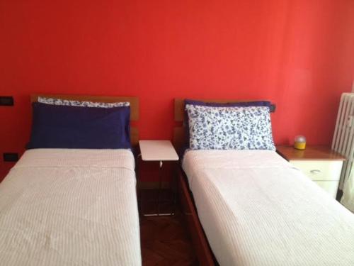 two beds in a room with a red wall at La casa di Johnny e Valentina in Milan