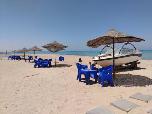 a beach with chairs and umbrellas and a boat at Home in ras sedr in Ras Sedr