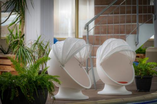 three white vases with umbrellas sitting next to plants at Snezhanka Hotel Pamporovo-All inclusive & Half Board in Pamporovo
