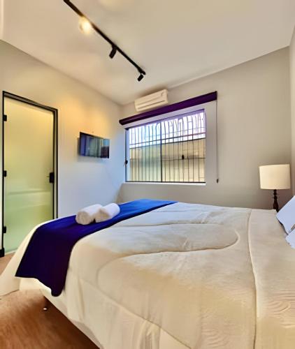 a bedroom with a large white bed with a window at KiTNETcompleta ótima localização in Curitiba