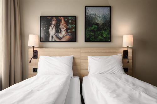 a bedroom with two beds and two paintings on the wall at Scandic Gardermoen in Gardermoen