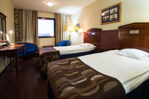 a hotel room with two beds and a desk at Scandic Pohjanhovi in Rovaniemi