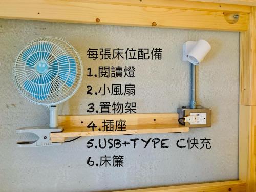 a wall with a fan and writing on it at The Moment Hostel Dulan in Donghe