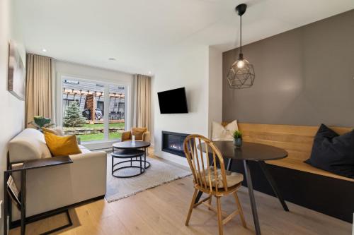 a living room with a table and a living room with a couch at Suites du Lac Moore by Manitonga in Mont-Tremblant