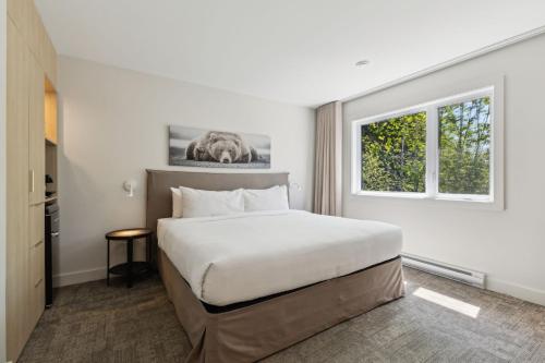 a hotel room with a bed and a window at Suites du Lac Moore by Manitonga in Mont-Tremblant