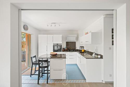 une cuisine avec des armoires blanches et une table et des chaises dans l'établissement Charmant RDJ T3 en Bord de Mer terrasse Carqueiranne By HC, à Carqueiranne