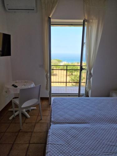 a bedroom with a bed and a table and a window at Casa Borrelli in Cittadella del Capo