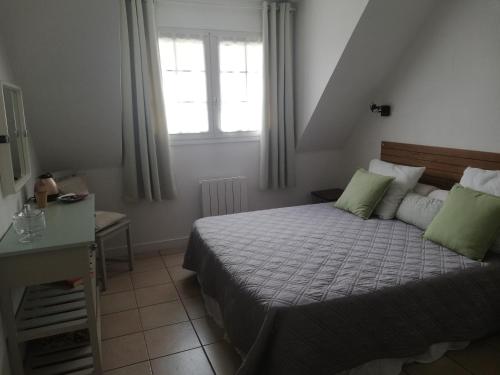 une chambre avec un lit avec des oreillers verts et une fenêtre dans l'établissement La Bretagne de Lila, à Lanester