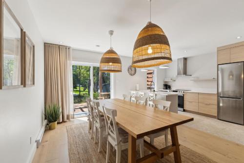 a kitchen and dining room with a wooden table and chairs at Condos Kamik Tremblant by Manitonga in Mont-Tremblant