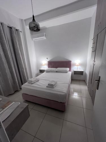 a white bedroom with a bed and two night stands at 4 seasons apartment 102 eco in Thiva