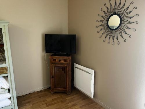a room with a television and a mirror on the wall at La maison Sainte Anne in Tour-en-Bessin