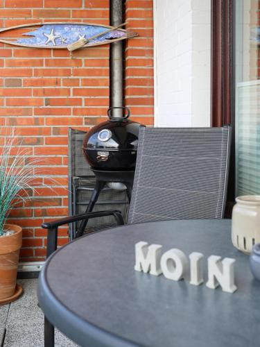 a table and chair with a stove in front of a brick wall at Nordseeblick in Büsum