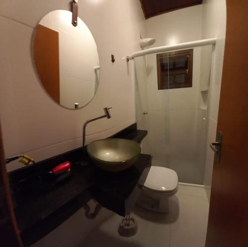 a bathroom with a sink and a toilet and a mirror at 01 Lindo apartamento na praia com piscina in São Sebastião