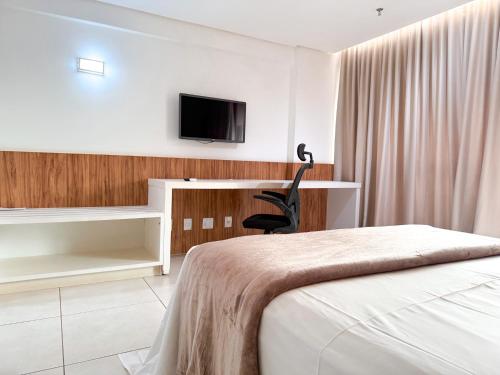a bedroom with a bed and a tv on a wall at STAY Vivence Suítes in Palmas
