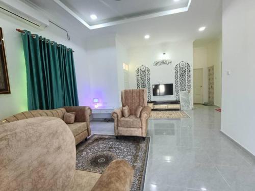 a living room with a couch and chairs and a tv at Aura Beach Homestay in Kampong Ru Sepuloh