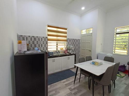a kitchen and dining room with a table and chairs at Aura Beach Homestay in Kampong Ru Sepuloh